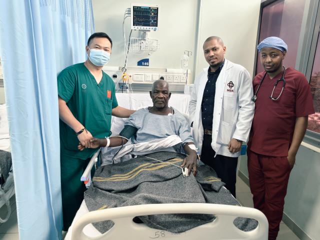 (251025) -- DAR ES SALAAM, Oct. 25, 2025 (Xinhua) -- Chinese and Tanzanian doctors pose for photos with patient Omar Haji Makame after a successful laparoscopic surgery at Lumumba Hospital in Zanzibar, Tanzania, Oct. 20, 2025. TO GO WITH "Feature: Tanzania's Zanzibar elder gains new lease on life through Chinese medical expertise" (The 35th Chinese medical team in Zanzibar/Handout via Xinhua)