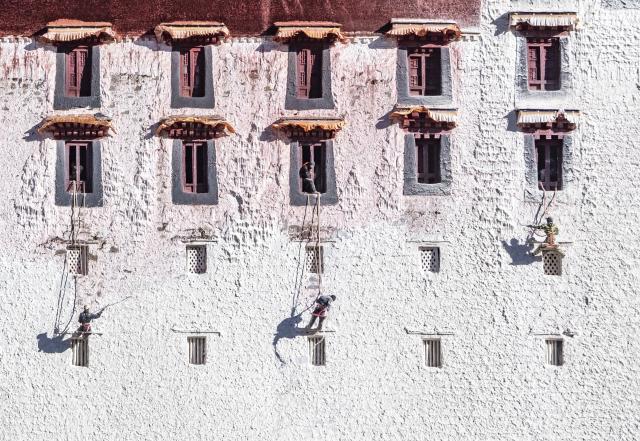 (251025) -- LHASA, Oct. 25, 2025 (Xinhua) -- Workers paint the wall of the Potala Palace during an annual renovation of the ancient architectural complex in Lhasa, southwest China's Xizang Autonomous Region, Oct. 24, 2025. (Photo by Tenzin Norbu/Xinhua)