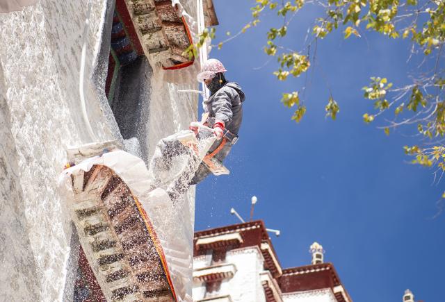 (251025) -- LHASA, Oct. 25, 2025 (Xinhua) -- A worker paints the wall of the Potala Palace during an annual renovation of the ancient architectural complex in Lhasa, southwest China's Xizang Autonomous Region, Oct. 24, 2025. (Photo by Tenzin Norbu/Xinhua)
