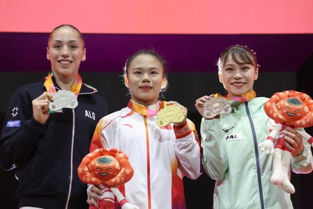 (251025) -- JAKARTA, Oct. 25, 2025 (Xinhua) -- Gold medalist Zhang Qingying (C) of China , silver medalist Kaylia Nemour (L) of Algeria and bronze medalist Sugihara Aiko of Japan pose for photos during the awarding ceremony for the women's balance beam final at 53rd FIG Artistic Gymnastics World Championships in Jakarta, Indonesia, on Oct. 25, 2025. (Xinhua/Bai Xuefei)