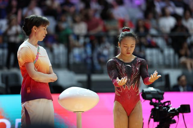 (251025) -- JAKARTA, Oct. 25, 2025 (Xinhua) -- Zhang Qingying (R) of China reacts during the women's Balance Beam Final at 53rd FIG Artistic Gymnastics World Championships in Jakarta, Indonesia, on Oct. 25, 2025. (Xinhua/Bai Xuefei)
