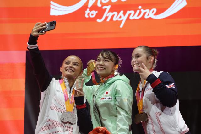 (251025) -- JAKARTA, Oct. 25, 2025 (Xinhua) -- Gold medalist Sugihara Aiko (C) of Japan, silver medalist Ruby Evans (L) of Britain and bronze medalist Abigail Martin of Britain take selfies during the awarding ceremony after the women's Floor Exercise Final at 53rd FIG Artistic Gymnastics World Championships in Jakarta, Indonesia, on Oct. 25, 2025. (Xinhua/Bai Xuefei)