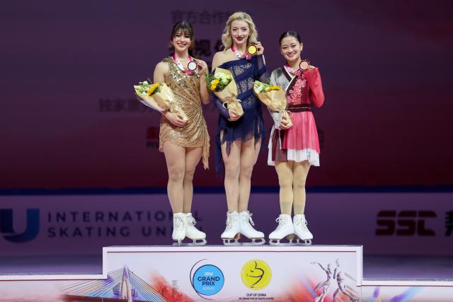 (251025) -- CHONGQING, Oct. 25, 2025 (Xinhua) -- Gold medalist Amber Glenn (C) of the United States, silver medalist Alysa Liu (L) of the United States and bronze medalist Watanabe Rinka of Japan pose for photos during the awarding ceremony for the women's singles skating at the Cup of China ISU Grand Prix of Figure Skating 2025 in southwest China's Chongqing Municipality, on Oct. 25, 2025. (Xinhua/Huang Wei)