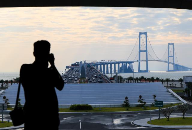 (251026) -- BEIJING, Oct. 26, 2025 (Xinhua) -- A man takes photos of the Shenzhen-Zhongshan Bridge from a viewing platform on the west artificial island of the Shenzhen-Zhongshan Link in south China's Guangdong Province, Oct. 25, 2025.
  The west artificial island of the Shenzhen-Zhongshan Link started trial operation for tourism on Saturday.
  The Shenzhen-Zhongshan Link, spanning approximately 24 kilometers, opened to traffic on June 30, 2024. (Xinhua/Mao Siqian)