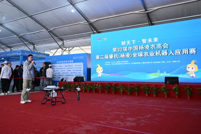 (251026) -- YANGLING, Oct. 26, 2025 (Xinhua) -- A contestant from Shaanxi National Defense Industry Technician College introduces an agricultural drone in a competition for agricultural robots during the 32nd China Yangling Agricultural Hi-Tech Fair in Yangling, northwest China's Shaanxi Province, Oct. 26, 2025. The agricultural hi-tech fair kicked off here on Saturday, highlighting a competition for agricultural robots as well as an exhibition on smart agricultural machinery. (Xinhua/Li Yibo)