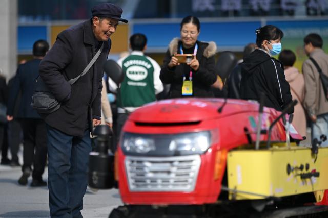 (251026) -- YANGLING, Oct. 26, 2025 (Xinhua) -- A visitor learns about a small-scale multi-functional ploughing machine with self-propelled tracks during the 32nd China Yangling Agricultural Hi-Tech Fair in Yangling, northwest China's Shaanxi Province, Oct. 26, 2025. The agricultural hi-tech fair kicked off here on Saturday, highlighting a competition for agricultural robots as well as an exhibition on smart agricultural machinery. (Xinhua/Li Yibo)