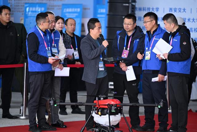 (251026) -- YANGLING, Oct. 26, 2025 (Xinhua) -- A technician presents an agricultural drone to the judges in a competition for agricultural robots during the 32nd China Yangling Agricultural Hi-Tech Fair in Yangling, northwest China's Shaanxi Province, Oct. 26, 2025. The agricultural hi-tech fair kicked off here on Saturday, highlighting a competition for agricultural robots as well as an exhibition on smart agricultural machinery. (Xinhua/Li Yibo)