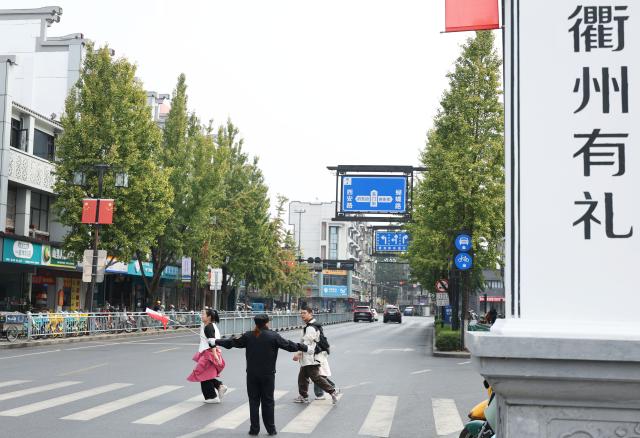 (251026) -- QUZHOU, Oct. 26, 2025 (Xinhua) -- A volunteer guides pedestrians to go across the road in Quzhou, east China's Zhejiang Province, Oct. 26, 2025. In recent years, Quzhou has been fostering a harmonious living environment by promoting Chinese etiquette education to the public and putting the idea of "good-mannered" into its governmental service. (Xinhua/Jin Haoyuan)