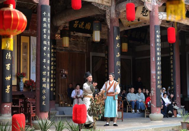(251026) -- QUZHOU, Oct. 26, 2025 (Xinhua) -- Tourists watch a performance themed on filial responsibility in Dachen Village of Quzhou, east China's Zhejiang Province, Oct. 25, 2025. In recent years, Quzhou has been fostering a harmonious living environment by promoting Chinese etiquette education to the public and putting the idea of "good-mannered" into its governmental service. (Xinhua/Jin Haoyuan)