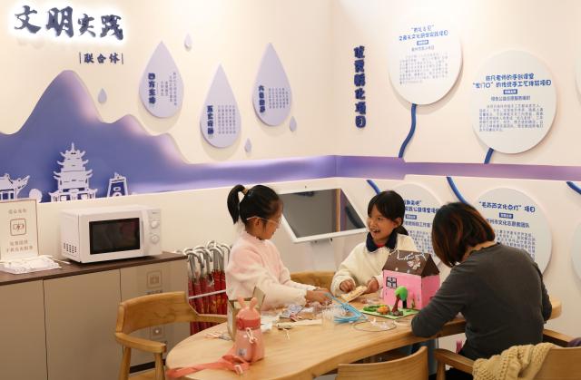 (251026) -- QUZHOU, Oct. 26, 2025 (Xinhua) -- A parent and children make handy crafts in Quzhou, east China's Zhejiang Province, Oct. 26, 2025. In recent years, Quzhou has been fostering a harmonious living environment by promoting Chinese etiquette education to the public and putting the idea of "good-mannered" into its governmental service. (Xinhua/Jin Haoyuan)