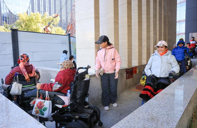 (251026) -- BEIJING, Oct. 26, 2025 (Xinhua) -- Physically impaired people leave Trojan Fairy restaurant after a film screening in Beijing, capital of China, Oct. 26, 2025. The Trojan Fairy restaurant, which focuses on supporting people with disabilities, hosted a film screening for 52 visually and physically impaired attendees. The event featured narrated audio descriptions to help visually impaired participants visualize scenes. (Xinhua/Yin Gang)