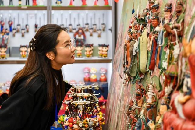 (251027) -- BEIJING, Oct. 27, 2025 (Xinhua) -- A tourist views dough figurine works, the intangible cultural heritage, in Xinzhou ancient city in Xinzhou, north China's Shanxi Province, on Oct. 21, 2025. Leisure tourism in Xinzhou ancient city remains booming in late autumn. Tourism activities such as bathing in hot springs, taking photos in ancient costumes, and watching intangible cultural heritage performances have attracted many tourists to visit the ancient city for a few days, to deeply immerse themselves in the unique charm of traditional culture. (Xinhua/Cao Yang)