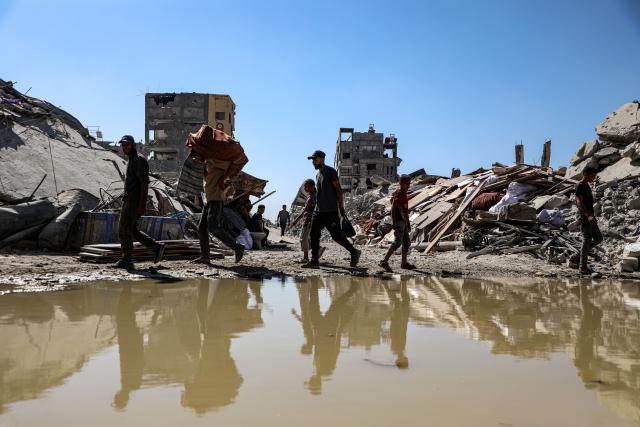 (251027) -- GAZA, Oct. 27, 2025 (Xinhua) -- Palestinians are seen at a street with destroyed buildings, in Jabalia refugee camp northern Gaza Strip, Oct. 27, 2025. The United Nations estimates that approximately 92 percent of all residential buildings in Gaza -- around 436,000 homes -- have been damaged or destroyed since the start of the conflict. (Photo by Rizek Abdeljawad/Xinhua)