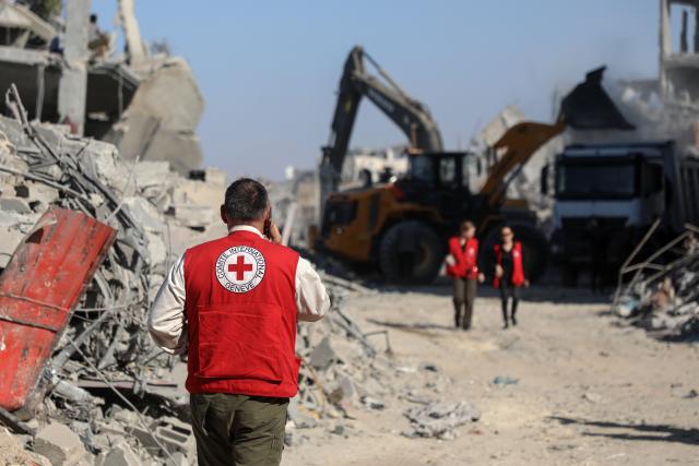 (251027) -- GAZA, Oct. 27, 2025 (Xinhua) -- Red Cross members are seen as an Egyptian Excavator is working at al-Tuffah area east of Gaza City, Oct. 27, 2025. Red Cross and Egyptian teams have been allowed to enter the Gaza Strip to search for the bodies of hostages, Israeli government spokesperson Shosh Bedrosian said on Sunday. (Photo by Rizek Abdeljawad/Xinhua)