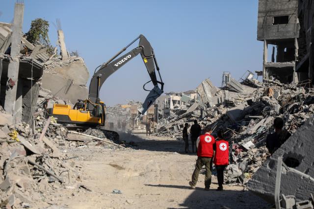 (251027) -- GAZA, Oct. 27, 2025 (Xinhua) -- Red Cross members are seen as an Egyptian Excavator is working at al-Tuffah area east of Gaza City, Oct. 27, 2025. Red Cross and Egyptian teams have been allowed to enter the Gaza Strip to search for the bodies of hostages, Israeli government spokesperson Shosh Bedrosian said on Sunday. (Photo by Rizek Abdeljawad/Xinhua)