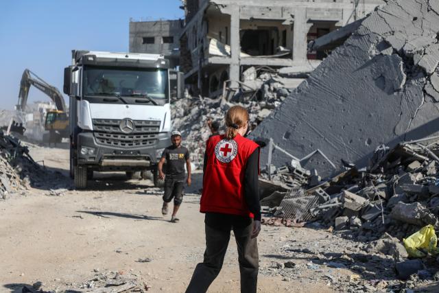 (251027) -- GAZA, Oct. 27, 2025 (Xinhua) -- A Red Cross member is seen as an Egyptian Excavator is working at al-Tuffah area east of Gaza City, Oct. 27, 2025. Red Cross and Egyptian teams have been allowed to enter the Gaza Strip to search for the bodies of hostages, Israeli government spokesperson Shosh Bedrosian said on Sunday. (Photo by Rizek Abdeljawad/Xinhua)