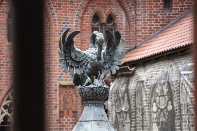 (251028) -- MALBORK, Oct. 28, 2025 (Xinhua) -- A pelican sculpture is seen in the courtyard of the high castle at the Malbork Castle in Malbork, Poland, Oct. 27, 2025. The Malbork Castle, also known as the Castle of the Teutonic Order, was built by the Teutonic Knights in the 13th century. The red-brick fortress covers about 200,000 square meters, making it one of the world's largest brick castles and a masterpiece of medieval Gothic military architecture. It was inscribed on the UNESCO World Heritage List in 1997 for its outstanding cultural and architectural value. (Xinhua/Xia Yuanyi)