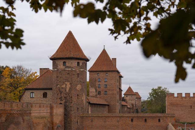 (251028) -- MALBORK, Oct. 28, 2025 (Xinhua) -- This photo taken on Oct. 27, 2025 shows towers of the outer section of the Malbork Castle in Malbork, Poland. The Malbork Castle, also known as the Castle of the Teutonic Order, was built by the Teutonic Knights in the 13th century. The red-brick fortress covers about 200,000 square meters, making it one of the world's largest brick castles and a masterpiece of medieval Gothic military architecture. It was inscribed on the UNESCO World Heritage List in 1997 for its outstanding cultural and architectural value. (Xinhua/Xia Yuanyi)