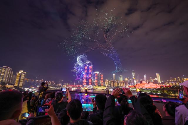 (251028) -- CHONGQING, Oct. 28, 2025 (Xinhua) -- People watch a drone light show in Nan'an District of southwest China's Chongqing Municipality, Oct. 27, 2025. A grand drone light show themed on "People-Centered Smart Cities Towards the Future" was staged here on Monday as a special event for the 2025 World Cities Day China Observance. (Xinhua/Huang Wei)