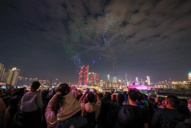 (251028) -- CHONGQING, Oct. 28, 2025 (Xinhua) -- People watch a drone light show in Nan'an District of southwest China's Chongqing Municipality, Oct. 27, 2025. A grand drone light show themed on "People-Centered Smart Cities Towards the Future" was staged here on Monday as a special event for the 2025 World Cities Day China Observance. (Xinhua/Huang Wei)