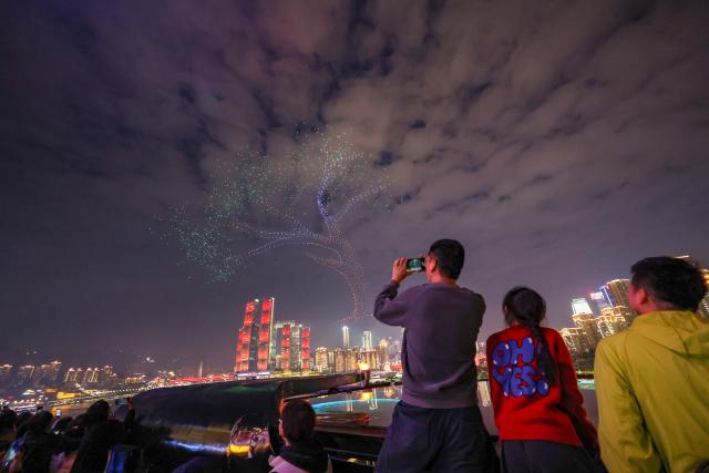 (251028) -- CHONGQING, Oct. 28, 2025 (Xinhua) -- People watch a drone light show in Nan'an District of southwest China's Chongqing Municipality, Oct. 27, 2025. A grand drone light show themed on "People-Centered Smart Cities Towards the Future" was staged here on Monday as a special event for the 2025 World Cities Day China Observance. (Xinhua/Huang Wei)