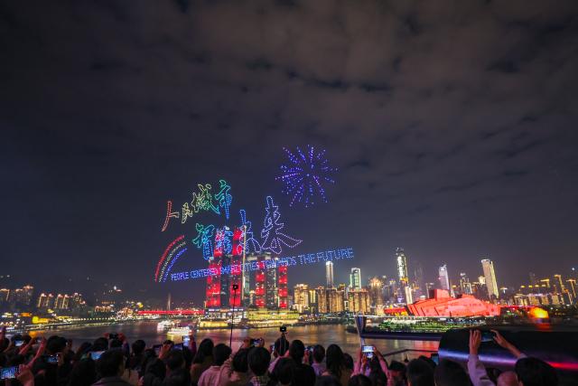 (251028) -- CHONGQING, Oct. 28, 2025 (Xinhua) -- People watch a drone light show in Nan'an District of southwest China's Chongqing Municipality, Oct. 27, 2025. A grand drone light show themed on "People-Centered Smart Cities Towards the Future" was staged here on Monday as a special event for the 2025 World Cities Day China Observance. (Xinhua/Huang Wei)