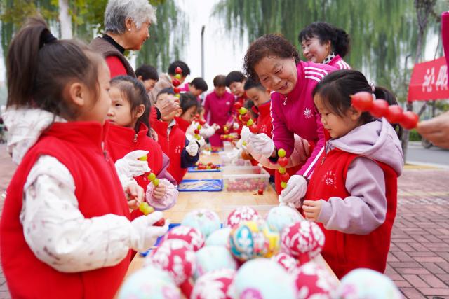 (251028) -- BEIJING, Oct. 28, 2025 (Xinhua) -- Children from a kindergarten make sweets together with elderly people in Qinyang City, central China's Henan Province, Oct. 28, 2025. A series of activities were held across the country to mark China's Chongyang Festival, which will fall on Oct. 29 this year. Also known as Seniors' Day in China nowadays, it highlights the public's care for elderly people. (Photo by Zhang Xinyu/Xinhua)