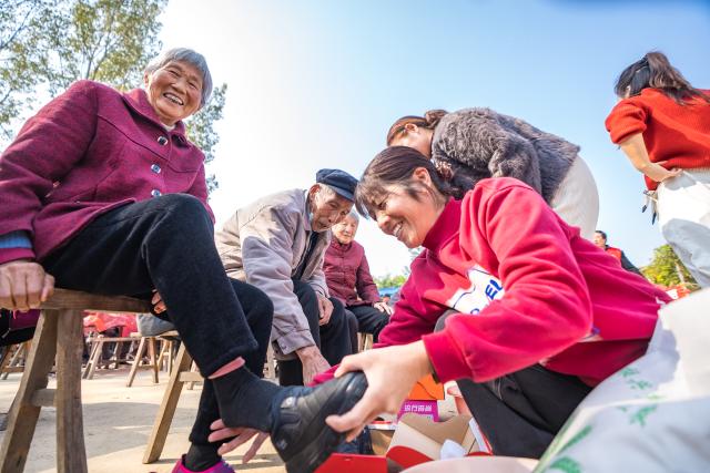 (251028) -- BEIJING, Oct. 28, 2025 (Xinhua) -- A staff member helps an elderly woman put on a pair of donated shoes in Baimiao Village, Zhumadian City, central China's Henan Province, Oct. 28, 2025. A series of activities were held across the country to mark China's Chongyang Festival, which will fall on Oct. 29 this year. Also known as Seniors' Day in China nowadays, it highlights the public's care for elderly people. (Photo by Zhao Yongtao/Xinhua)