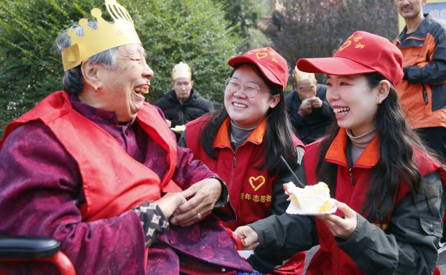 (251028) -- BEIJING, Oct. 28, 2025 (Xinhua) -- Volunteers hand a piece of cake to an elderly woman at a nursing home in Chengguan Town of Luoyang, central China's Henan Province, Oct. 28, 2025. A series of activities were held across the country to mark China's Chongyang Festival, which will fall on Oct. 29 this year. Also known as Seniors' Day in China nowadays, it highlights the public's care for elderly people. (Photo by Kang Hongjun/Xinhua)