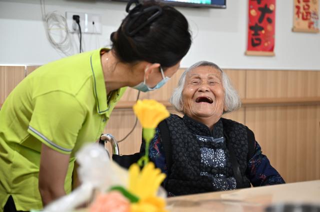 (251029) -- BEIJING, Oct. 29, 2025 (Xinhua) -- An elderly person chats with a staff worker at an elderly care service center in Qiongshan District of Haikou, south China's Hainan Province, Oct. 29, 2025.
  A series of celebration activities were held across the country to mark Chongyang Festival, which falls on Oct. 29 this year. Also known as China's Seniors' Day, it honors the country's traditional virtues of filial piety and family love. (Xinhua/Guo Cheng)