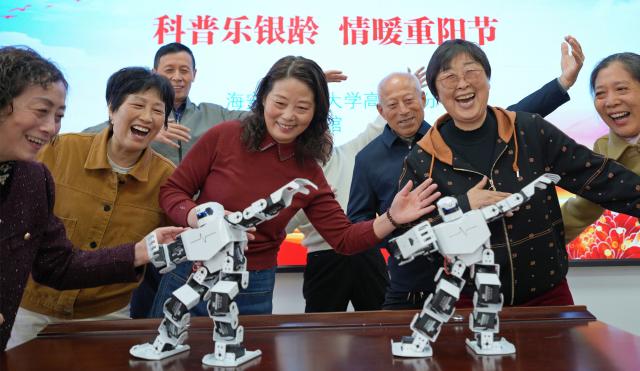 (251029) -- BEIJING, Oct. 29, 2025 (Xinhua) -- Senior citizens dance following the demonstration of robots at a school for seniors in Hai'an City, east China's Jiangsu Province, Oct. 29, 2025. A series of celebration activities were held across the country to mark Chongyang Festival, which falls on Oct. 29 this year. Also known as China's Seniors' Day, it honors the country's traditional virtues of filial piety and family love. (Photo by Zhou Qiang/Xinhua)