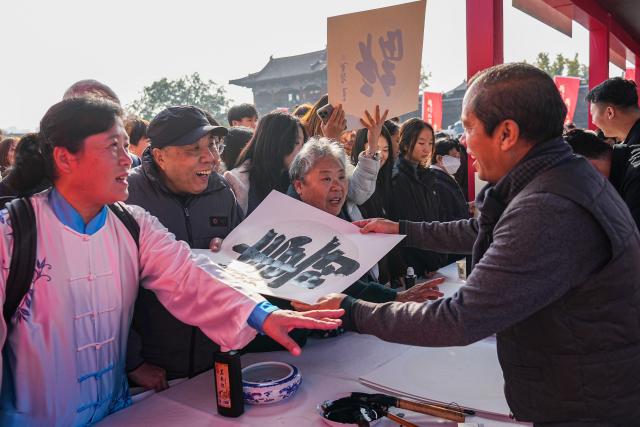(251029) -- BEIJING, Oct. 29, 2025 (Xinhua) -- A local artist gives a calligraphy work of Chinese character "shou", meaning longevity, to a senior citizen at an event celebrating Chongyang Festival in Tai'an City, east China's Shandong Province, Oct. 29, 2025. A series of celebration activities were held across the country to mark Chongyang Festival, which falls on Oct. 29 this year. Also known as China's Seniors' Day, it honors the country's traditional virtues of filial piety and family love. (Xinhua/Zhu Zheng)