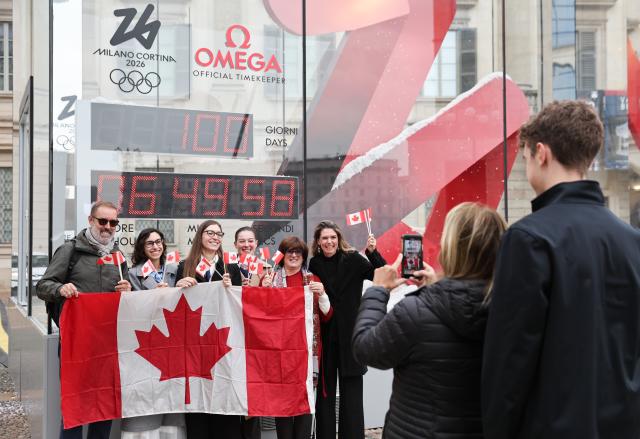 (251030) -- MILAN, Oct. 30, 2025 (Xinhua) -- Staff of Canadian embassy to Italy take a photo with the digital countdown timer of Milano-Cortina 2026 Olympic Games in Milan, Italy, Oct. 29, 2025. A ceremony marking 100 days to the opening of the Milano-Cortina 2026 Olympic Winter Games was held at Palazzo Lombardia in Milan, where organizers unveiled the official podiums for the Olympic and Paralympic Games and introduced 12 "digital torchbearers", symbolizing the start of the final stage of preparations for the event. (Xinhua/Li Jing)