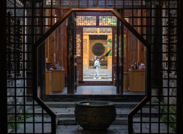 (251030) -- CHIBI, Oct. 30, 2025 (Xinhua) -- A tourist visits the ancient street in Yangloudong of Chibi City, central China's Hubei Province, Oct. 29, 2025. Yangloudong has long been renowned as the hometown of brick tea and is one of the starting points of an ancient tea road. In recent years, the area has built a new tourism model to attract tourists by creating intangible cultural heritage themed blocks and introducing diversified business formats such as Hanfu-renting and photograph. (Xinhua/Du Zixuan)