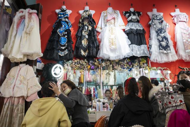 (251030) -- CHIBI, Oct. 30, 2025 (Xinhua) -- Tourists have their makeup applied at a travel photography studio on the ancient street in Yangloudong of Chibi City, central China's Hubei Province, Oct. 29, 2025. Yangloudong has long been renowned as the hometown of brick tea and is one of the starting points of an ancient tea road. In recent years, the area has built a new tourism model to attract tourists by creating intangible cultural heritage themed blocks and introducing diversified business formats such as Hanfu-renting and photograph. (Xinhua/Wu Zhizun)