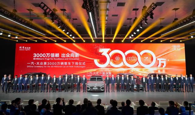 (251030) -- CHANGCHUN, Oct. 30, 2025 (Xinhua) -- Guests pose for a group photo with the 30 millionth car manufactured by FAW-Volkswagen at an offline ceremony in Changchun, northeast China's Jilin Province, Oct. 30, 2025. The offline ceremony celebrating the 30 millionth car rolling off the FAW-Volkswagen production line was held here on Thursday. (Xinhua/Xu Chang)