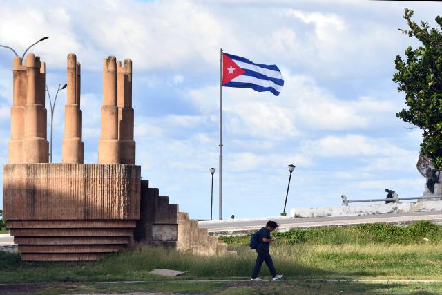 (251030) -- HAVANA, Oct. 30, 2025 (Xinhua) -- A pedestrian passes a Cuban National Flag in Havana, capital of Cuba, on Oct. 29, 2025. The UN General Assembly (UNGA) adopted a draft resolution on Wednesday urging the United States to end its economic, commercial and financial embargo against Cuba. Since 1992, the UNGA has adopted by an overwhelming majority the non-binding annual resolution, urging the United States to end its embargo against Cuba imposed since 1962. (Photo by Joaquin Hernandez/Xinhua)