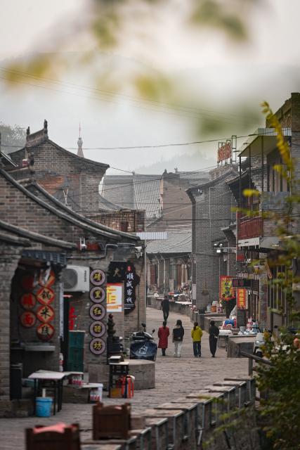 (251031) -- TAIYUAN, Oct. 31, 2025 (Xinhua) -- People walk in the Qikou ancient town of Linxian County, north China's Shanxi Province, Oct. 30, 2025. Qikou, an ancient town along the Yellow River, was an important trade ferry in history, where merchants unloaded goods such as fur, wool and herbs from boats coming upriver and switched to land transportation to further deliver them to cites like Taiyuan, Beijing, and Tianjin. Such a geographical advantage made Qikou an important port until the 1970s.
   However, Qikou's glory gradually faded in the following decades as land transportation network improved along the Yellow River area.
   In recent years, local government has been making efforts to renovate and protect the historical buildings and ancient residences here, promoting the integrated development of culture and tourism. (Photo by Liu Liangliang/Xinhua)