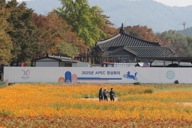 (251031) -- GYEONGJU, Oct. 31, 2025 (Xinhua) -- Tourists are seen near a publicity board of the 32nd Asia-Pacific Economic Cooperation (APEC) Economic Leaders' Meeting in Gyeongju, South Korea, Oct. 31, 2025. The first session of the 32nd APEC Economic Leaders' Meeting was held in Gyeongju on Friday. (Xinhua/Yao Qilin)