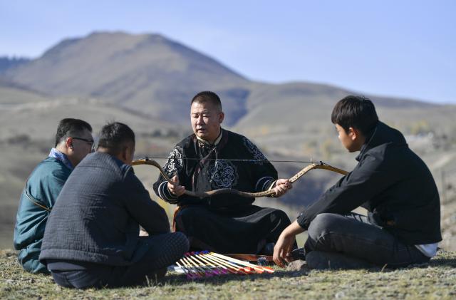 (251031) -- QAPQAL, Oct. 31, 2025 (Xinhua) -- Wu Junliang is a 37-year-old archer from Qapqal Xibe Autonomous County, a border county in northwest China's Xinjiang Uygur Autonomous Region - also proudly known as the hometown of Chinese archery. Wu is a recognized inheritor of the national intangible cultural heritage "Traditional Xibe Archery" and he has joined the "heritage-in-schools" initiative, offering free archery training to primary school students. He is called the "champion coach" by students.
Recognized for his strong arms and steady composure, Wu was admitted to a local archery school at the age of 16 to receive professional training. With outstanding talent, he quickly emerged, winning gold and silver medals in competitions at various levels. After retiring, he was hired as an archery coach for visitors at the Xibe Ancient Town.
For over a decade, Wu further studied traditional bows and taught himself multiple skills including horseback archery and rapid shooting at moving targets. As traditional bow competitions increased, he participated nationwide, winning multiple championships and training a number of apprentices. 
As intangible-heritage tourism gains popularity in recent years, Wu opened a 300-square-meter archery club in Yining City earlier this year, highlighting traditional bow culture. Wu Junliang (2nd R) gives a lecture about the craftsmanship of traditional bow making on a hill in Qapqal Xibe Autonomous County, northwest China's Xinjiang Uygur Autonomous Region, on Oct. 24, 2025. (Xinhua/Hu Huhu)
