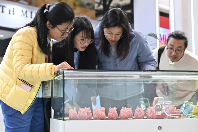 (251031) -- BEIJING, Oct. 31, 2025 (Xinhua) -- People view creative cultural products made of scraps of banknotes during the Beijing International Coin Exposition 2025 at the China National Convention Center in Beijing, capital of China, Oct. 31, 2025. The three-day exposition kicked off here on Friday, attracting 323 exhibitors from 21 countries and regions. (Xinhua/Li Xin)