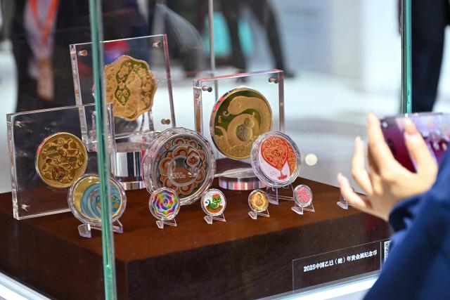 (251031) -- BEIJING, Oct. 31, 2025 (Xinhua) -- A visitor takes photos of commemorative coins issued for the Year of the Snake during the Beijing International Coin Exposition 2025 at the China National Convention Center in Beijing, capital of China, Oct. 31, 2025. The three-day exposition kicked off here on Friday, attracting 323 exhibitors from 21 countries and regions. (Xinhua/Li Xin)