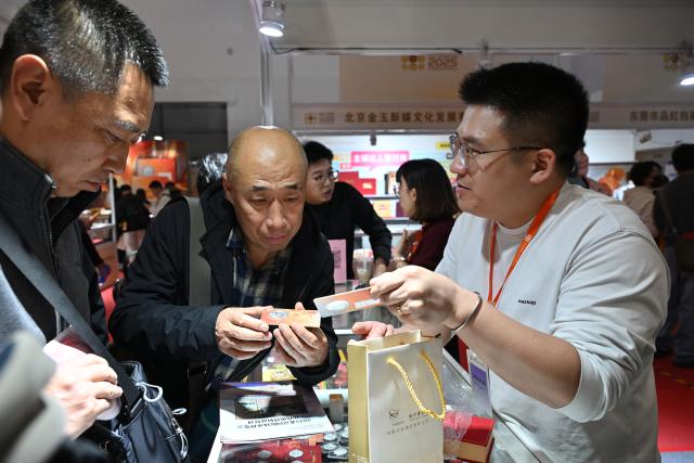 (251031) -- BEIJING, Oct. 31, 2025 (Xinhua) -- People select commemorative coins during the Beijing International Coin Exposition 2025 at the China National Convention Center in Beijing, capital of China, Oct. 31, 2025. The three-day exposition kicked off here on Friday, attracting 323 exhibitors from 21 countries and regions. (Xinhua/Li Xin)