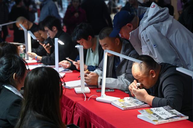 (251031) -- BEIJING, Oct. 31, 2025 (Xinhua) -- People learn about items during an auction preview of the Beijing International Coin Exposition 2025 at the China National Convention Center in Beijing, capital of China, Oct. 31, 2025. The three-day exposition kicked off here on Friday, attracting 323 exhibitors from 21 countries and regions. (Xinhua/Li Xin)