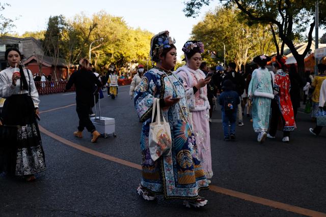(251101) -- BEIJING, Nov. 1, 2025 (Xinhua) -- Tourists wearing traditional Chinese costumes walk by Donghua Gate, as known as East Prosperity Gate of the Palace Museum in Beijing, capital of China, Nov. 1, 2025. (Xinhua/Wang Lili)
