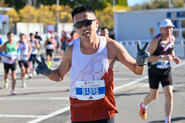 (251102) -- BEIJING, Nov. 2, 2025 (Xinhua) -- A participant celebrates after finishing the Beijing Marathon 2025 in Beijing, capital of China, Nov. 2, 2025. (Xinhua/Li Xulun)