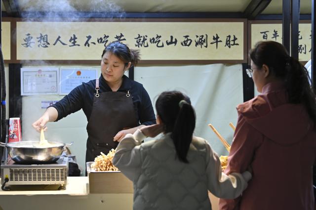 (251102) -- TAIYUAN, Nov. 2, 2025 (Xinhua) -- People buy food at Zhonglou Street in Taiyuan, north China's Shanxi Province, Nov. 1, 2025. As both a commercial hub and cultural landmark of Taiyuan, Zhonglou Street carries a millennium of local history. However, rapid urban development once left it struggling with aging facilities, narrow spaces, and traffic congestion.
     In 2020, Taiyuan launched a renovation project for the area, and by September of 2021, the historic street renewed with a fresh look. The upgrade preserved the traditional street layout and architectural style while integrating modern elements and functions, attracting numerous locals and tourists daily.
    In 2022, Zhonglou Street was listed among the second batch of national nighttime cultural and tourism consumption clusters. In 2023, it was included in the second batch of national-level tourism and leisure blocks. During this year's National Day holiday, nearly 900,000 visits were made to the street, cementing its status as a true "city living room." (Xinhua/Yang Chenguang)