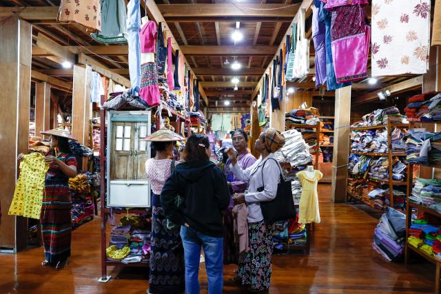 (251102) -- YANGON, Nov. 2, 2025 (Xinhua) -- Visitors shop at a hand-weaving workshop on Inle Lake in Nyaungshwe township, Shan state, Myanmar, Oct. 31, 2025. TO GO WITH "Feature: With patient hands, Myanmar's Inthas weave lotus fibers into world's handcrafted luxury" (Xinhua/Myo Kyaw Soe)