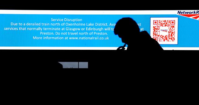 (251103) -- LONDON, Nov. 3, 2025 (Xinhua) -- A man stands next to a screen showing information on changes to rail services at Euston Station in London, Britain, Nov. 3, 2025. A train carrying 87 people derailed in northwestern England on Monday, disrupting rail services, local media reported. (Xinhua/Li Ying)