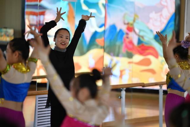 (251104) -- LANZHOU, Nov. 4, 2025 (Xinhua) -- A teacher instructs students Dunhuang dance at a primary school in Dunhuang, northwest China's Gansu Province, April 26, 2023.
  Dunhuang dance refers to a dance style that aims to bring to life the iconic figures depicted on the ancient murals of the Mogao Grottoes, which is a 1,600-year-old UNESCO World Heritage site in Dunhuang.
  Drawing on historical themes, contemporary artists have created four awe-inspiring music and dance masterpieces, which include the classic dance drama "Flower Rains Along Silk Road," whose footprints have covered more than 40 countries and regions since its debut in 1979, and "the Thousand-Hand Bodhisattva" performed by dancers with hearing or visual impairment.
  Last year, the four classic performing arts attracted more than 1.14 million visitors to Dunhuang, with a record of over 2,000 performances, according to data from the cultural and tourism department of Gansu Province. Through these cultural and visual feasts, tourists are immersed in the history of the ancient Silk Road, carrying forward Dunhuang's ongoing journey of cultural preservation.
  The introduction of Dunhuang dance to local educational institutions also fuels the boom. The unique dance genre has been passed down among young generations, promoting it to a wider audience so that more people will learn about the beauty of Dunhuang. (Xinhua/Chen Bin)